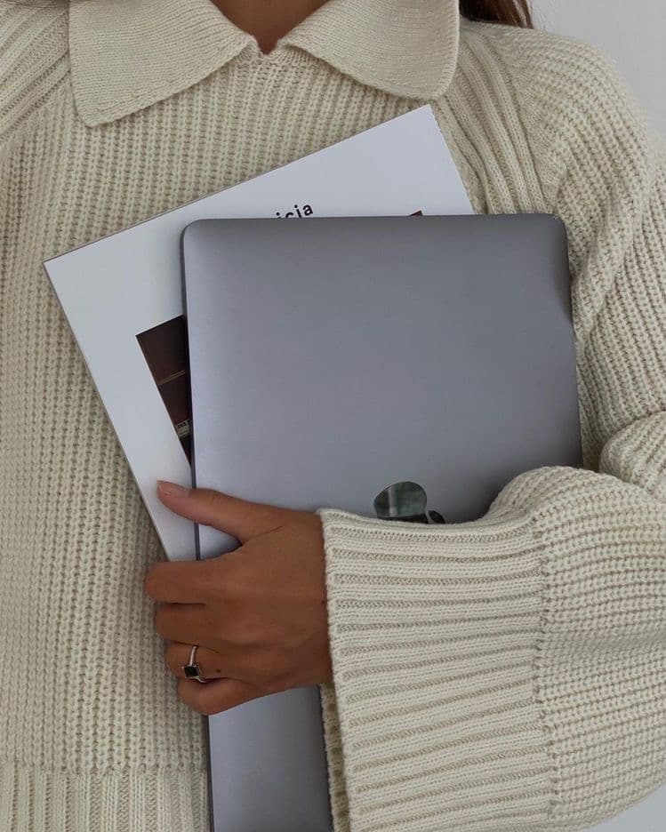 Persona sosteniendo un portátil y documentos de trabajo.